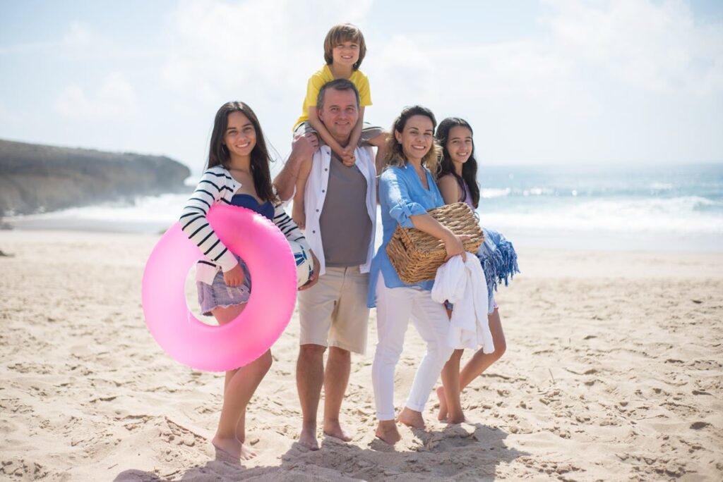 pexels-photo-8623333 A family of five posing happily on a sunny beach in Portugal, capturing summer memories.